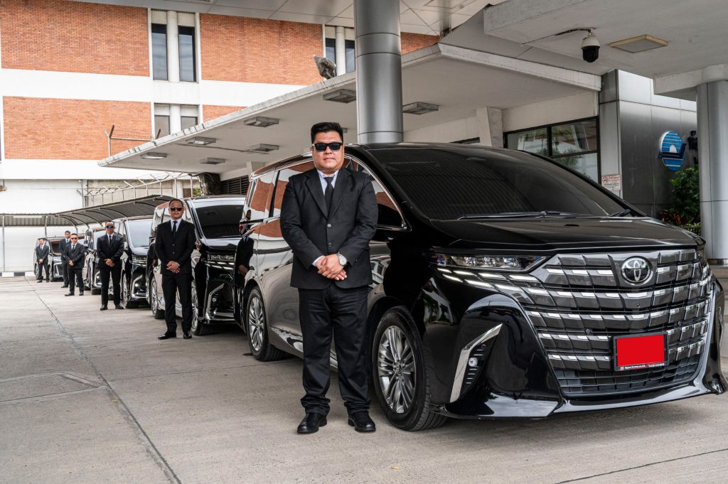คนขับมืออาชีพยืนข้างรถ Toyota Alphard สีดำ พร้อมให้บริการเช่ารถอัลพาร์ดรับส่งสนามบิน