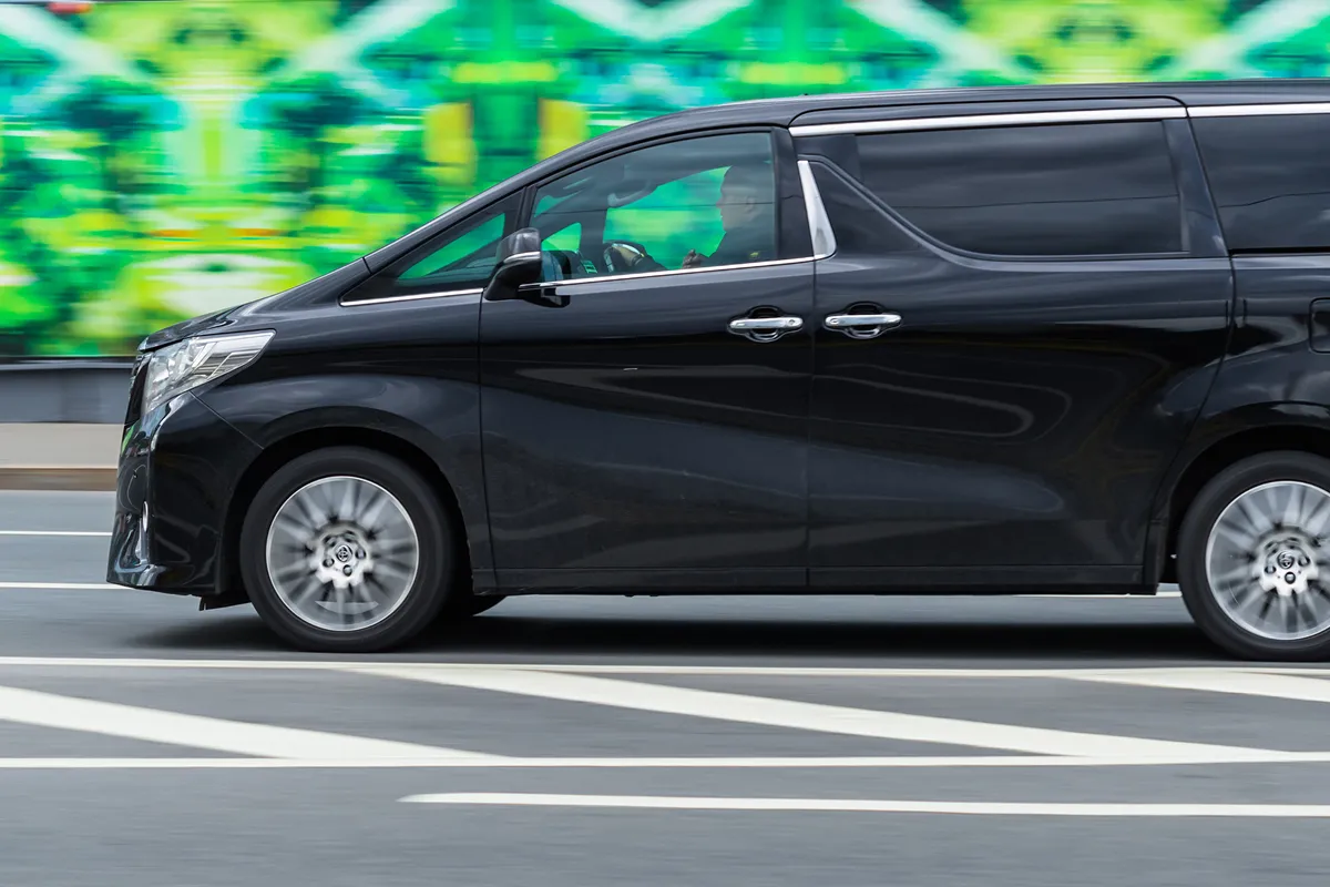 บริการเช่ารถ Alphard สีดำวิ่งบนถนนในเมือง